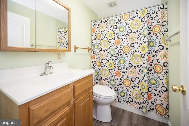 full bathroom featuring visible vents, a shower with shower curtain, toilet, vanity, and wood finished floors