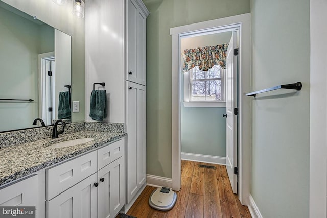 bathroom featuring baseboards, wood finished floors, and vanity