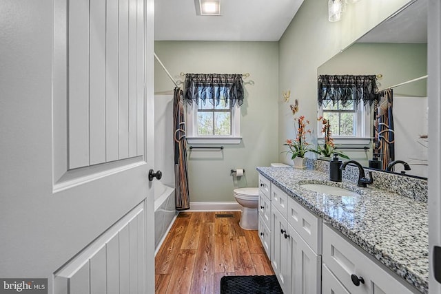 full bathroom featuring a healthy amount of sunlight, shower / bathtub combination with curtain, toilet, and wood finished floors