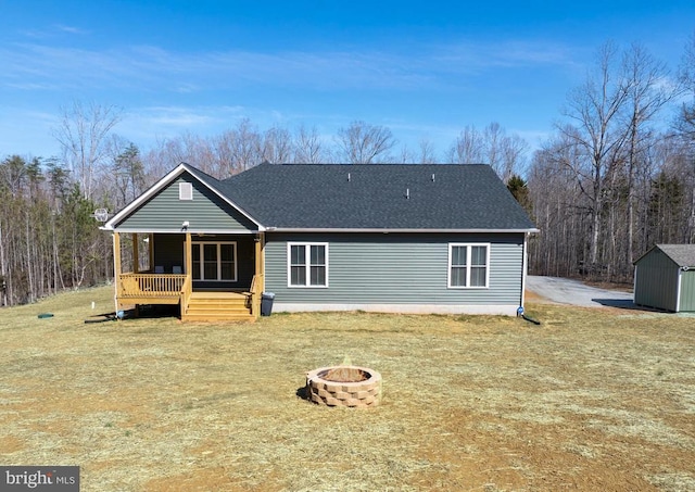 rear view of property featuring an outbuilding, roof with shingles, an outdoor fire pit, a porch, and a storage unit