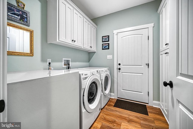 clothes washing area featuring cabinet space, wood finished floors, baseboards, and separate washer and dryer