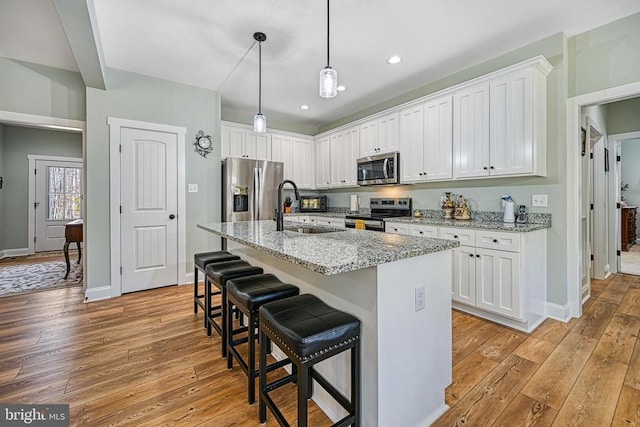 kitchen with light wood-style flooring, appliances with stainless steel finishes, white cabinets, and a sink