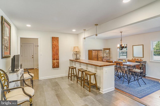 kitchen with a chandelier, a breakfast bar area, recessed lighting, a peninsula, and wooden counters