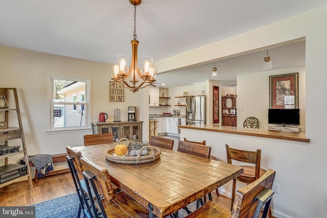 dining area featuring baseboards, a chandelier, and wood finished floors