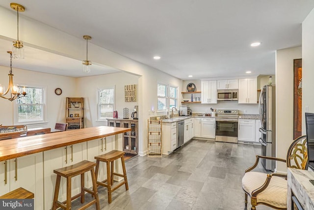 kitchen with recessed lighting, butcher block countertops, white cabinetry, appliances with stainless steel finishes, and decorative light fixtures