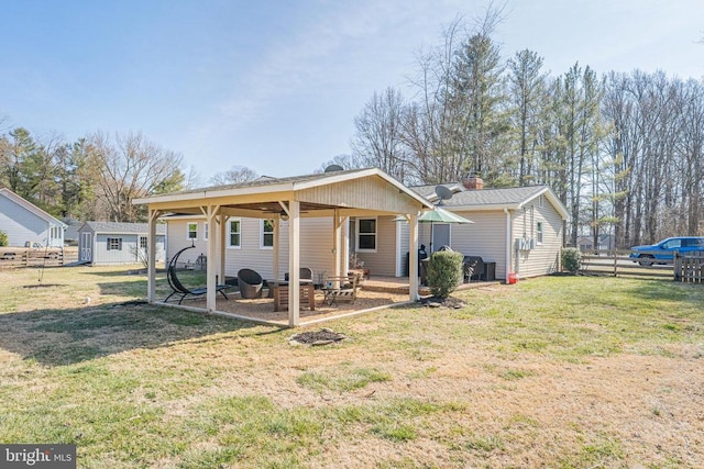 rear view of property with a yard, fence, an outdoor structure, and a patio