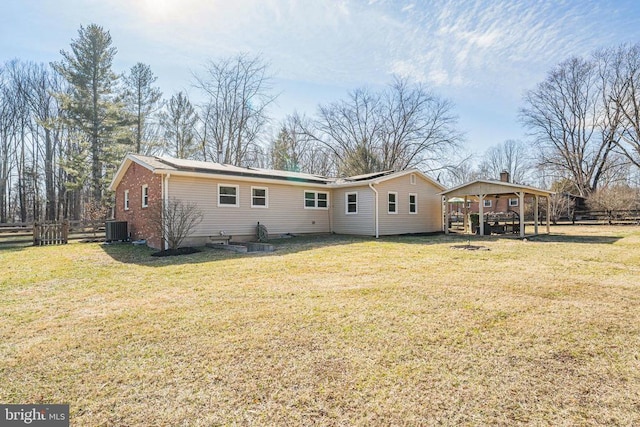 rear view of property featuring central AC, fence, brick siding, and a lawn