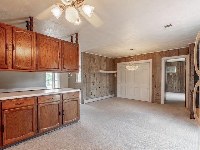 kitchen with wood walls, light carpet, hanging light fixtures, baseboard heating, and ceiling fan