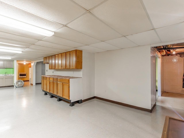 interior space with a drop ceiling, sink, and heating unit