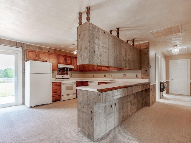 kitchen with sink, white appliances, a textured ceiling, kitchen peninsula, and light colored carpet