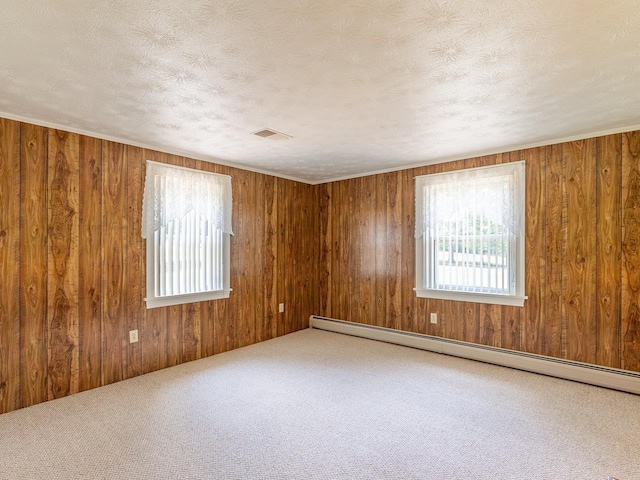 empty room with a baseboard radiator, wooden walls, a textured ceiling, and carpet flooring