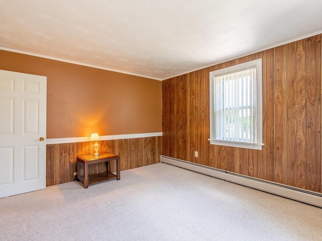 unfurnished room with baseboard heating, ornamental molding, carpet floors, and wood walls