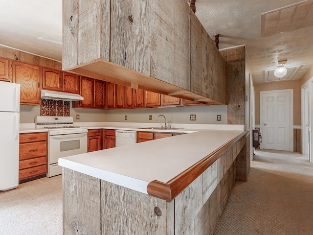 kitchen featuring sink, a textured ceiling, white appliances, and kitchen peninsula