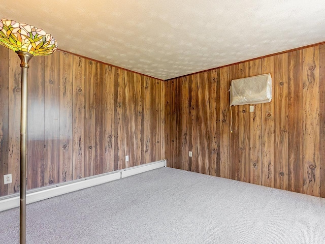 unfurnished room featuring baseboard heating, carpet, a textured ceiling, and wood walls