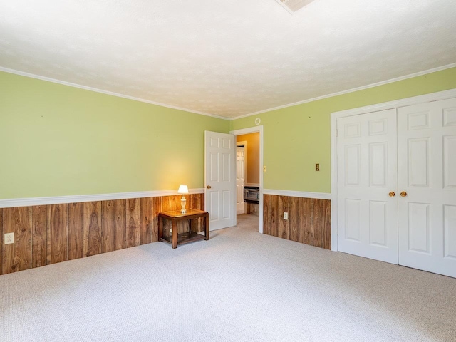 carpeted bedroom featuring crown molding, wooden walls, and a closet