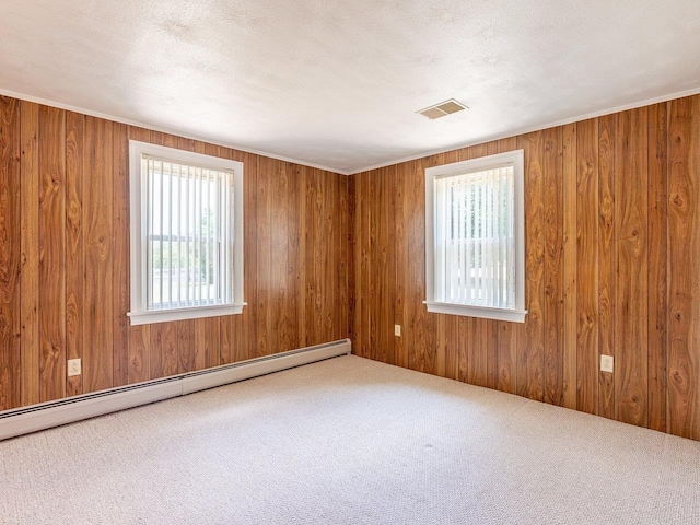 carpeted empty room featuring baseboard heating, wooden walls, and a textured ceiling