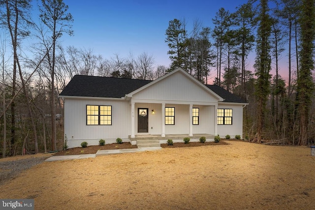 modern farmhouse style home featuring covered porch and roof with shingles