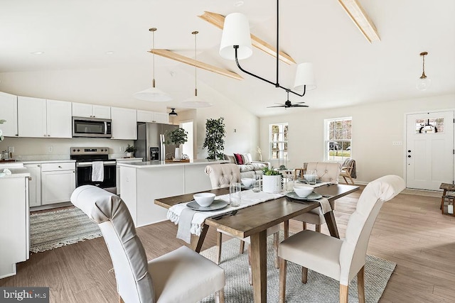 dining space featuring light wood-style flooring, a ceiling fan, and high vaulted ceiling