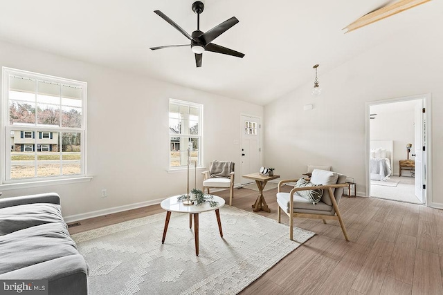 living area with visible vents, lofted ceiling, a ceiling fan, light wood-style floors, and baseboards