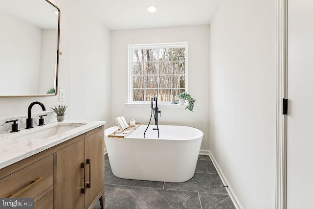 full bath featuring baseboards, a soaking tub, and vanity