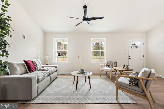 living room featuring visible vents, baseboards, ceiling fan, and wood finished floors