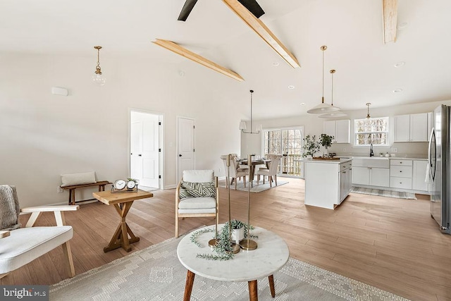 living area with baseboards, light wood-style floors, and high vaulted ceiling