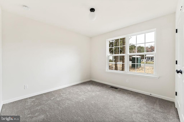 empty room featuring carpet, visible vents, and baseboards