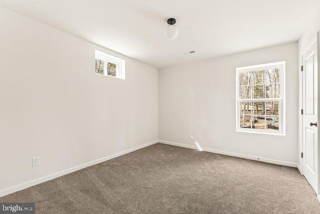 spare room with visible vents, a healthy amount of sunlight, baseboards, and carpet floors