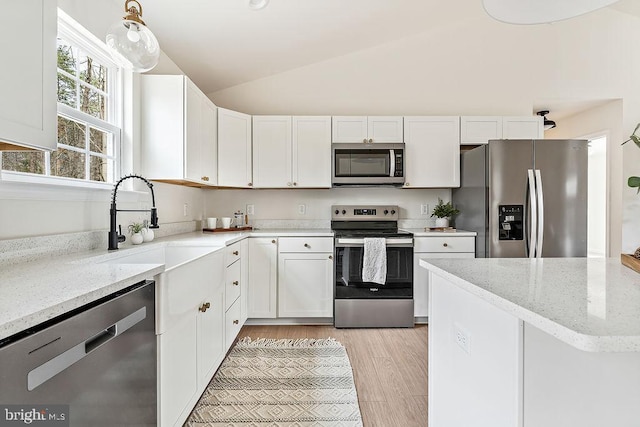 kitchen featuring vaulted ceiling, white cabinets, light stone countertops, and appliances with stainless steel finishes