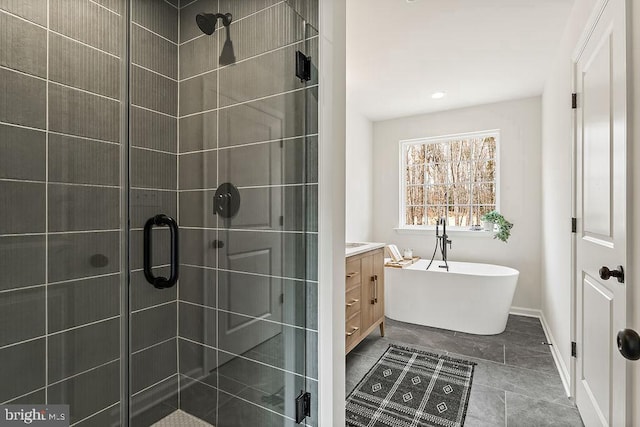 full bath with baseboards, a freestanding bath, a stall shower, and vanity