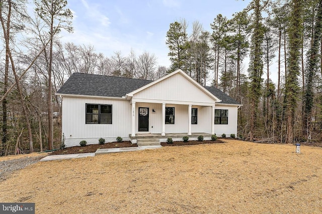 modern farmhouse featuring a porch and roof with shingles