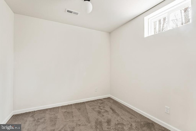 unfurnished room with carpet, visible vents, and baseboards