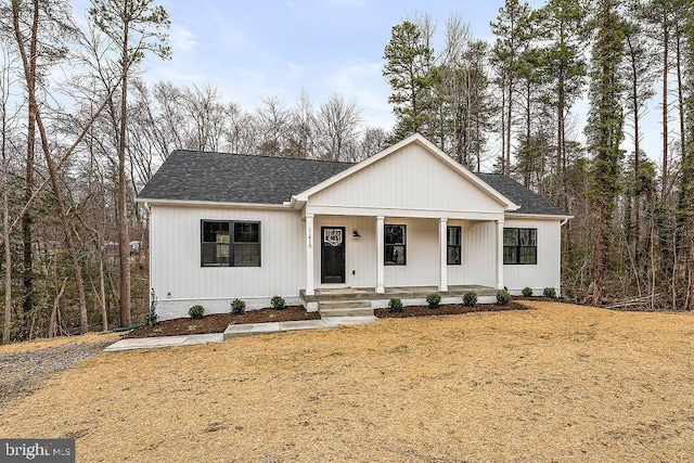 modern farmhouse style home featuring covered porch and a shingled roof