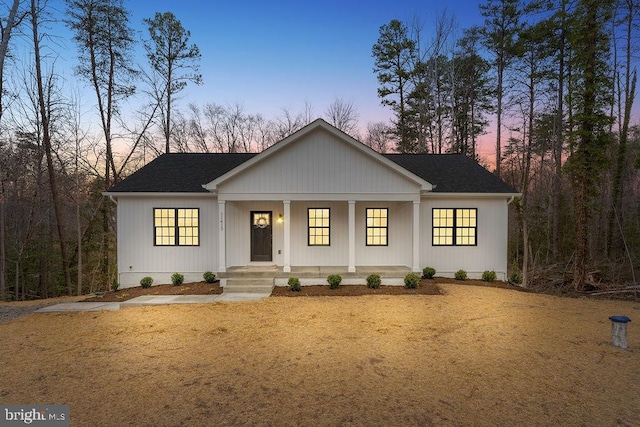 modern inspired farmhouse featuring covered porch and a shingled roof