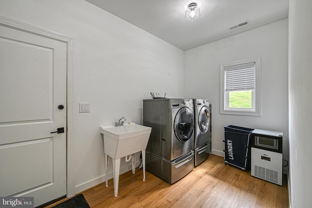 clothes washing area featuring hardwood / wood-style flooring and washing machine and clothes dryer