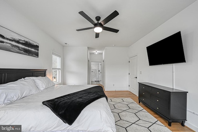 bedroom with ceiling fan, ensuite bathroom, and light hardwood / wood-style flooring