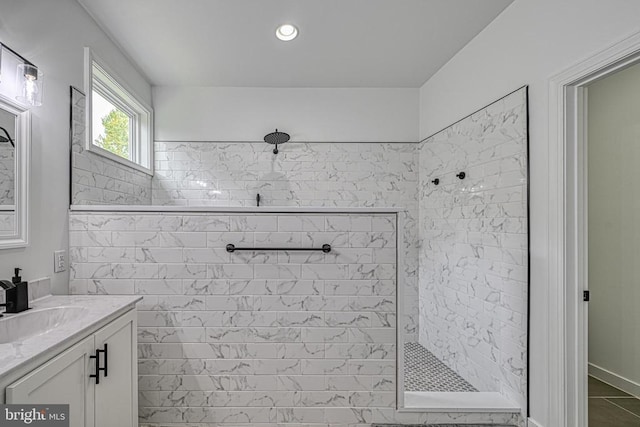 bathroom with a tile shower and vanity