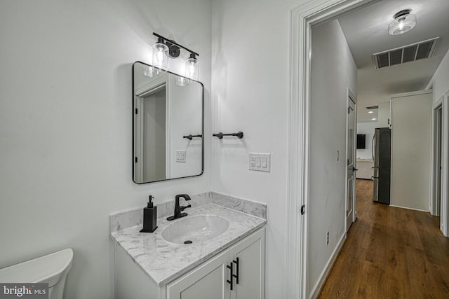 bathroom with vanity, toilet, and wood-type flooring