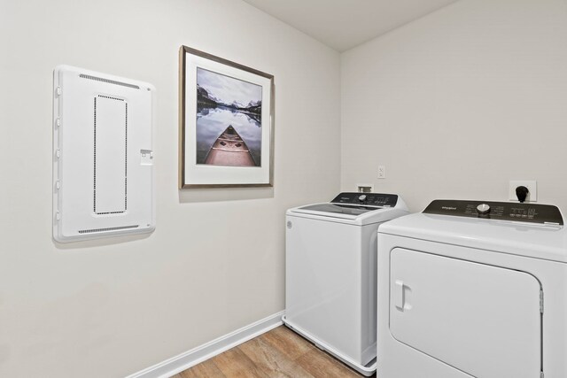 laundry room with washing machine and clothes dryer and light wood-type flooring