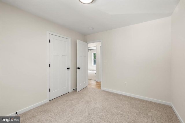 unfurnished bedroom with light colored carpet and baseboards