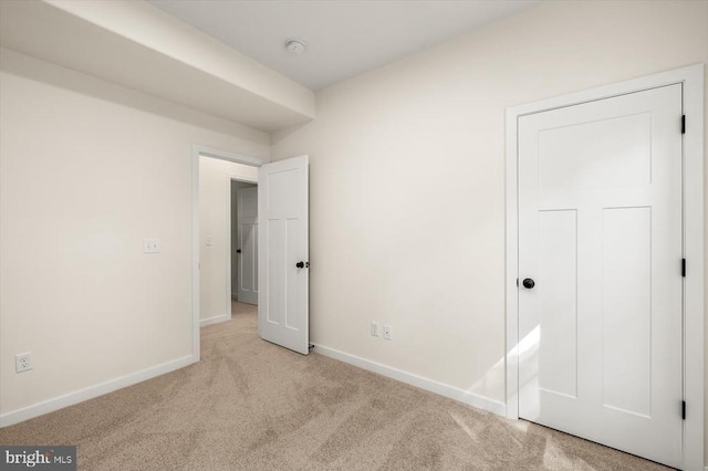 unfurnished bedroom with baseboards and light colored carpet