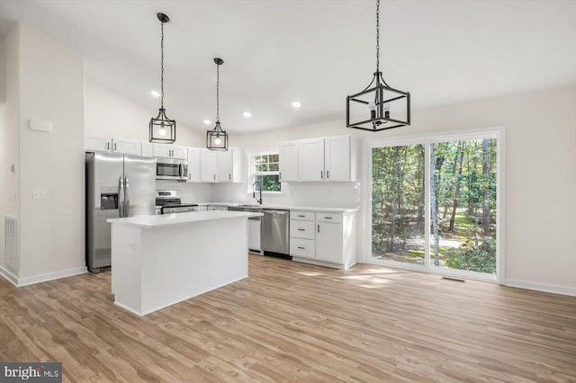 kitchen featuring white cabinets, appliances with stainless steel finishes, decorative light fixtures, a center island, and light countertops