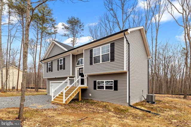 bi-level home featuring a garage, driveway, and central air condition unit