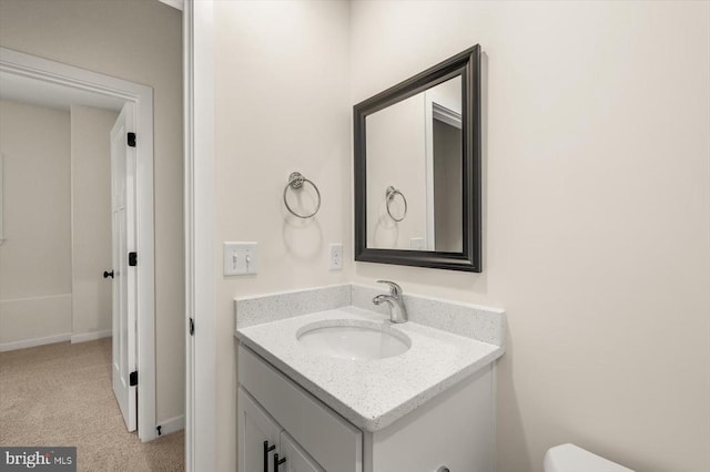 bathroom with toilet, vanity, and baseboards