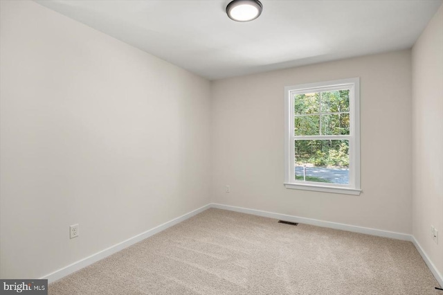 carpeted empty room featuring visible vents and baseboards