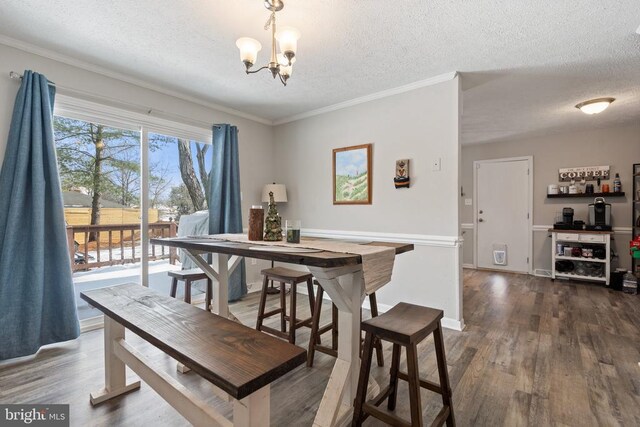 dining room with a notable chandelier, a textured ceiling, and wood finished floors