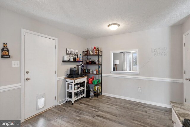 interior space with a textured ceiling, wood finished floors, and baseboards