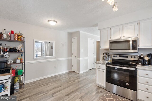 kitchen featuring stainless steel appliances, light countertops, and white cabinetry