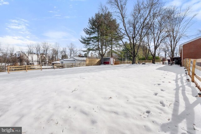 yard layered in snow featuring an outdoor structure, a storage shed, and fence