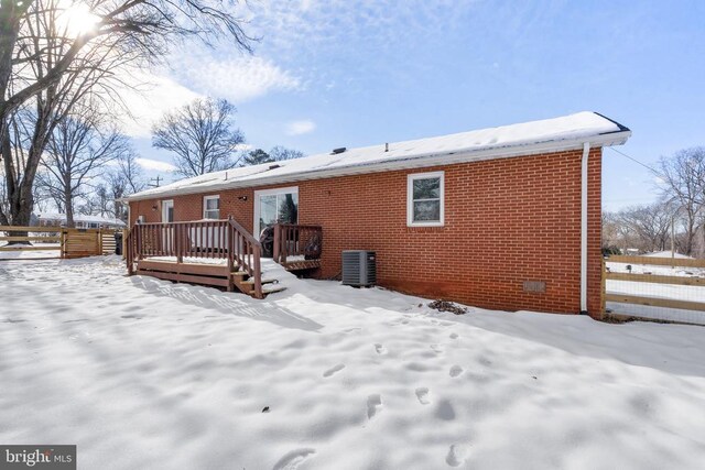 snow covered property with crawl space, brick siding, a wooden deck, and central AC unit